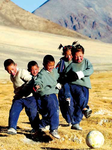 Tibetan kids are kicking the ball on the grassland in Rutok County of Ngari Prefecture(over 4300 meters high).
