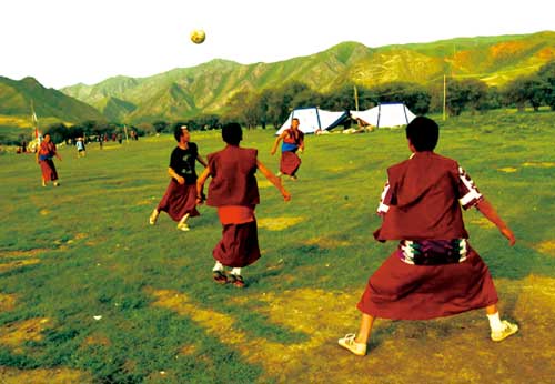 Young monks are kicking the ball during their leisure time.